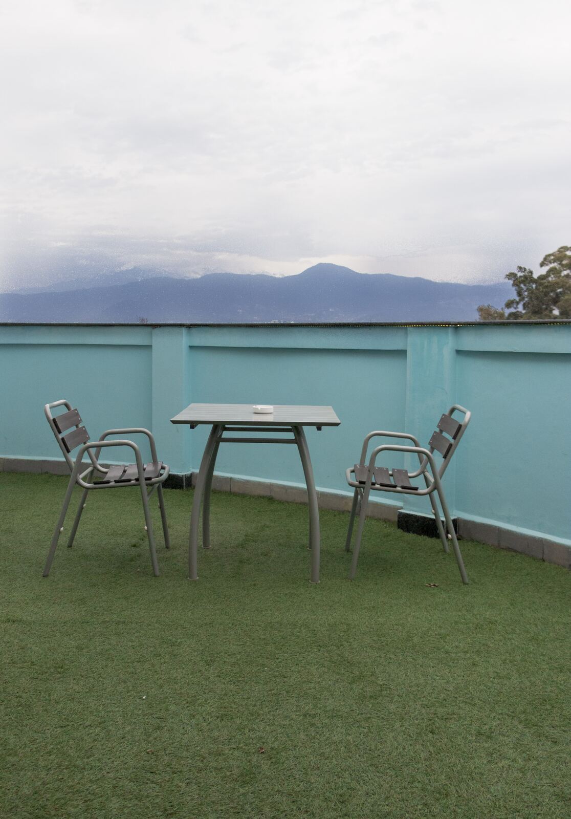 The private balcony, laid with artificial grass, with a table and chairs.