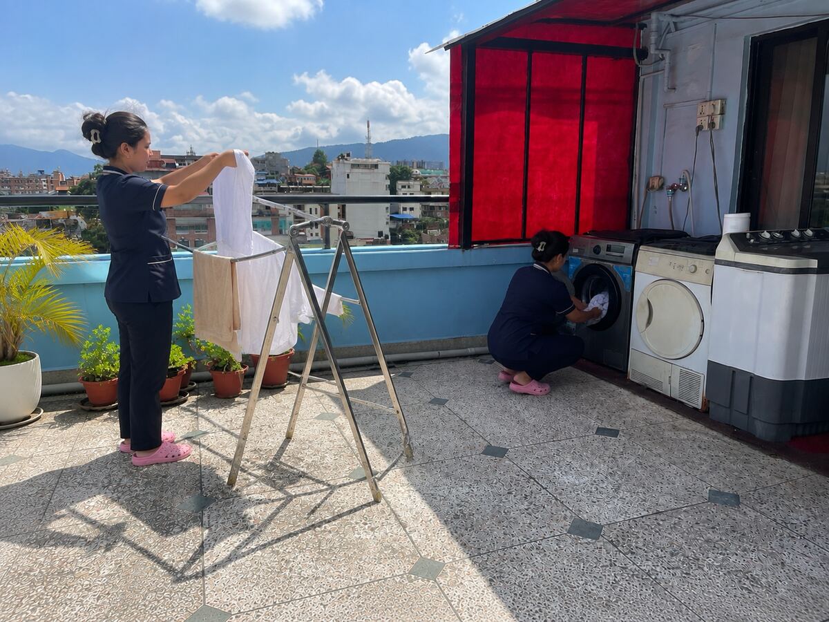 The rooftop laundry area: washing machines under cover and a drying rack in the open air, with the city beyond.